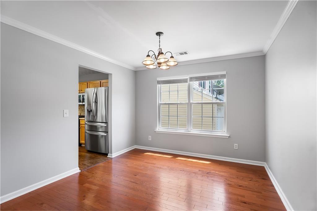411 Sugar Maple Court Canton, GA 30114 - Photo 14 of 34 an empty room with wooden floor chandelier and windows