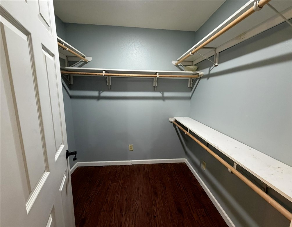5108 Ridge Road Alma, AR 72921 - Photo 26 of 33 Walk-in closet featuring wood-finish flooring, light blue walls, white trim, and built-in shelving with hanging rods