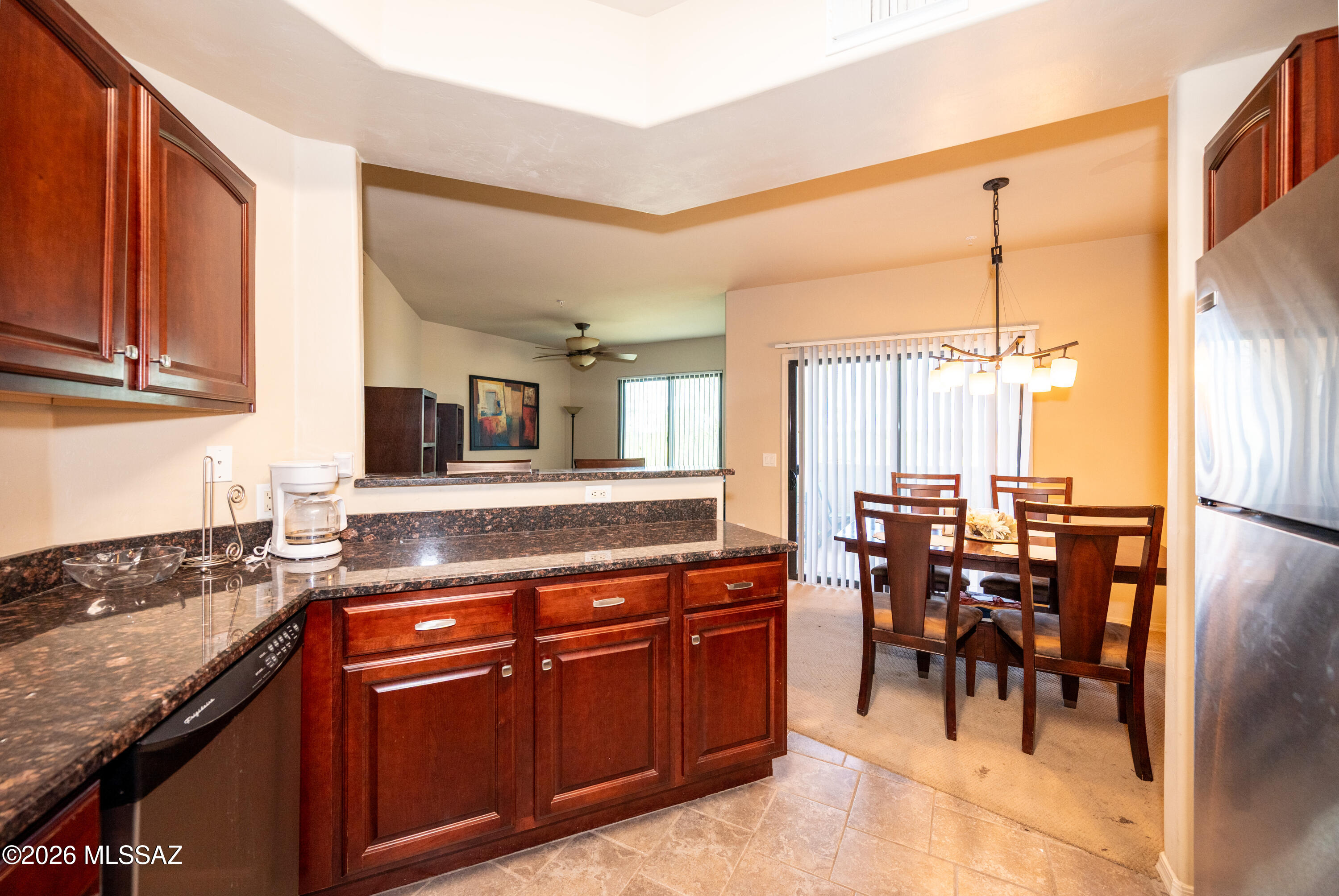 2550 East River Road, Unit 15303 Tucson, AZ 85718 - Photo 5 of 15 a kitchen with stainless steel appliances granite countertop wooden cabinets a dining table and chairs