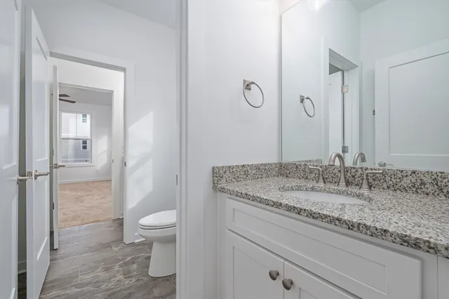 a bathroom with a granite countertop sink a toilet and a shower