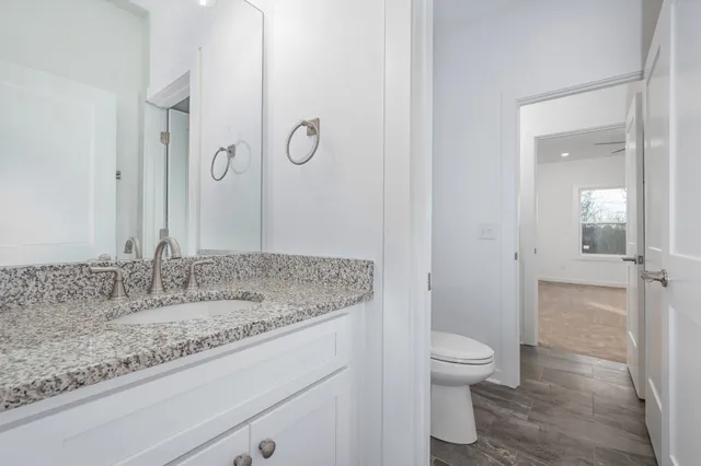 a bathroom with a granite countertop sink a toilet and shower