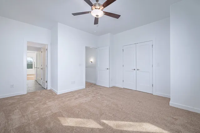 a view of an empty room and chandelier fan