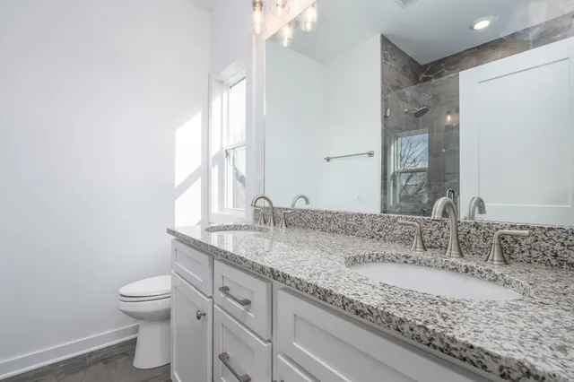 a bathroom with a granite countertop sink a toilet and a mirror