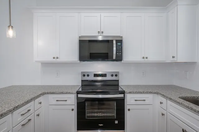 a kitchen with granite countertop white cabinets and a stove