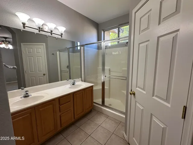 a bathroom with a double vanity sink mirror and shower