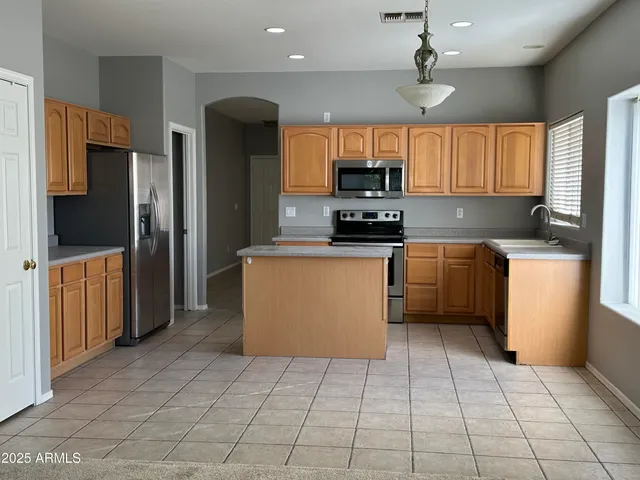 a kitchen with stainless steel appliances a sink a stove a refrigerator cabinets and a window