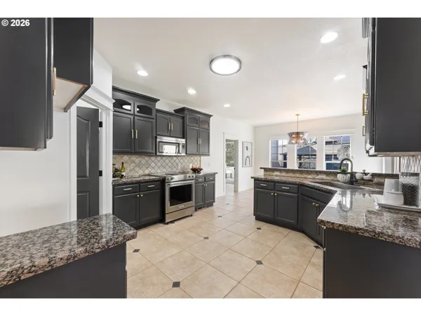 a large kitchen with granite countertop a large counter top stainless steel appliances and cabinets