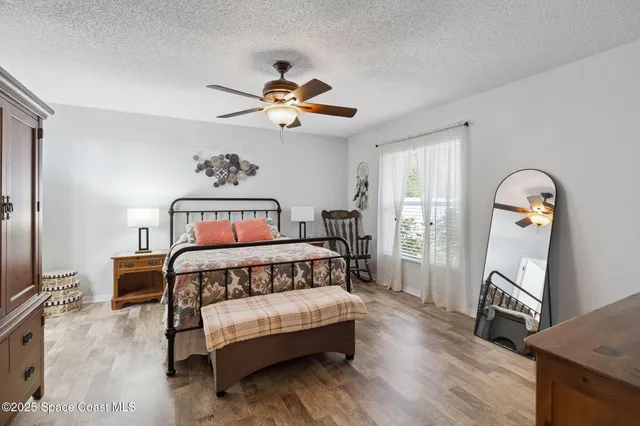 a bedroom with a bed a dresser and wooden floor