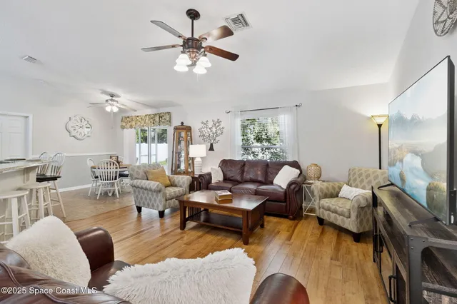 a living room with furniture kitchen view and a large window