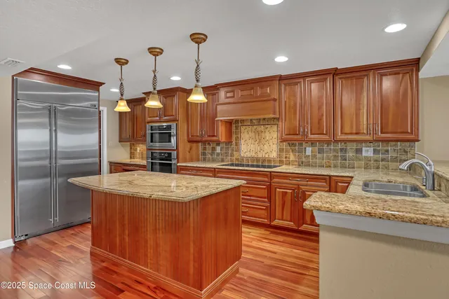 a kitchen with stainless steel appliances granite countertop a sink a microwave oven and a center island with wooden floor