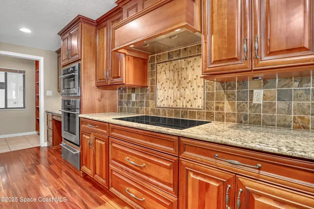 a view of kitchen with granite countertop cabinets and refrigerator