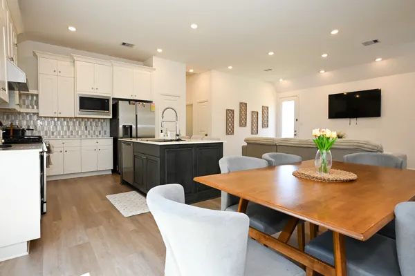 a kitchen with stainless steel appliances kitchen island granite countertop a sink a stove a microwave a dining table and chairs