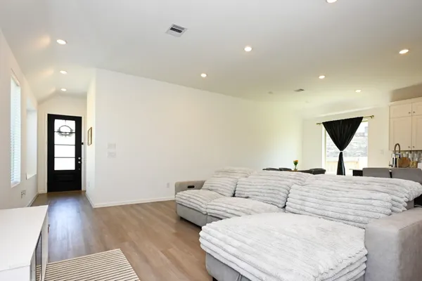 a living room with couches and kitchen view with wooden floor