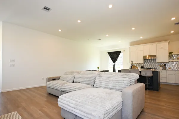 a living room with couches and kitchen view with wooden floor