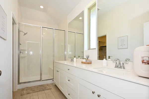 a bathroom with a double vanity sink mirror and shower