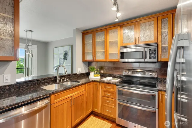 a kitchen with stainless steel appliances granite countertop a sink stove and cabinets