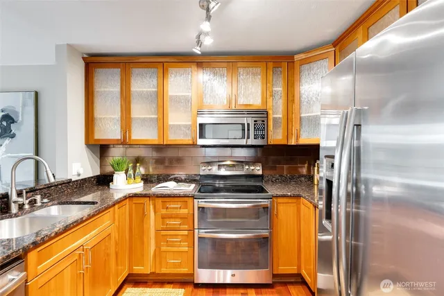 a kitchen with stainless steel appliances granite countertop a sink a stove and a refrigerator