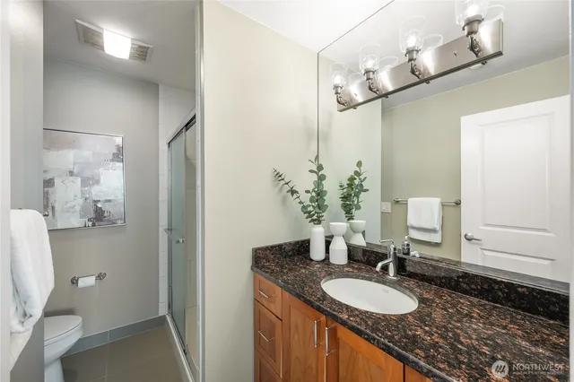 a bathroom with a granite countertop sink a toilet and a mirror