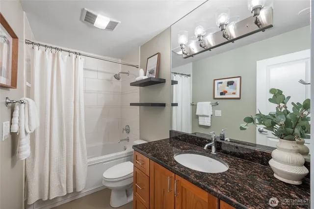 a bathroom with a granite countertop toilet a sink and a mirror