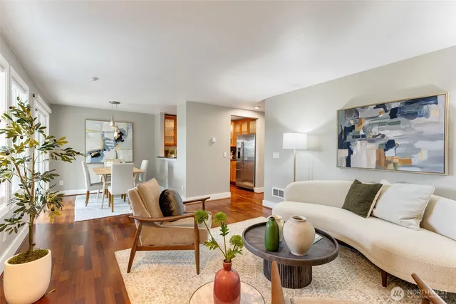 a living room with furniture a dining table and a large mirror with wooden floor