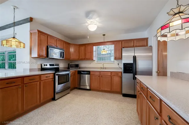 a kitchen with stainless steel appliances granite countertop a sink a stove a refrigerator cabinets and a window