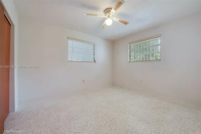an empty room with a window and a fan