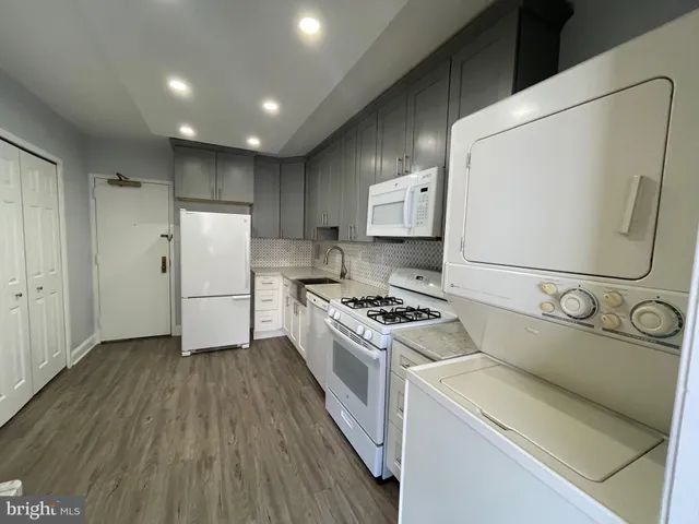 a kitchen with a refrigerator a stove and white cabinets