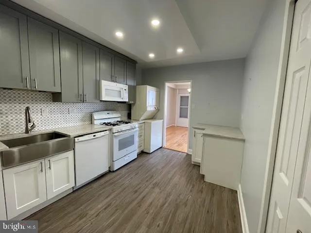 a kitchen with granite countertop wooden floors appliances and cabinets