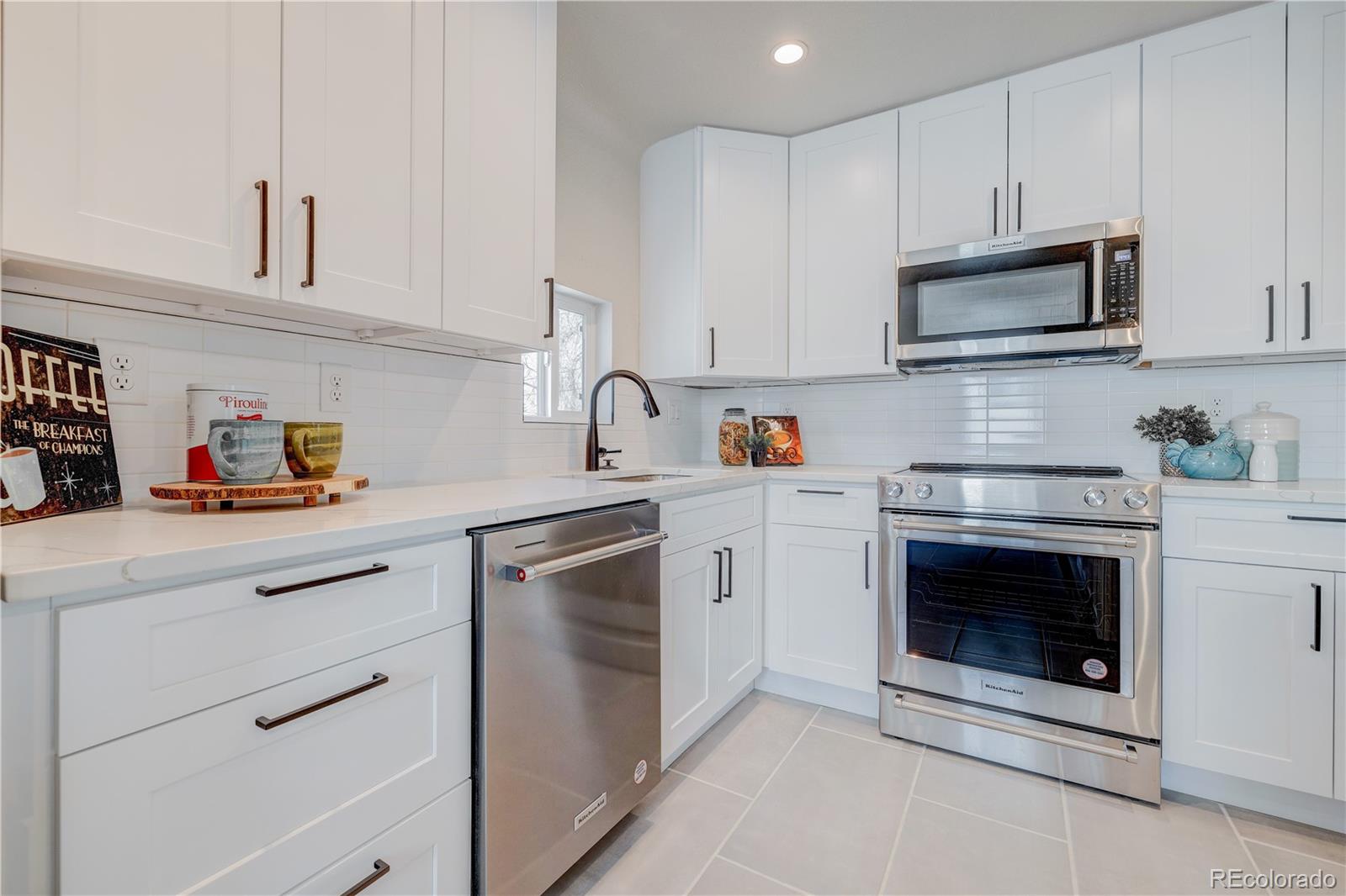 2932 Chase Street Wheat Ridge, CO 80214 - Photo 11 of 30 a kitchen with stainless steel appliances granite countertop white cabinets a sink and a stove