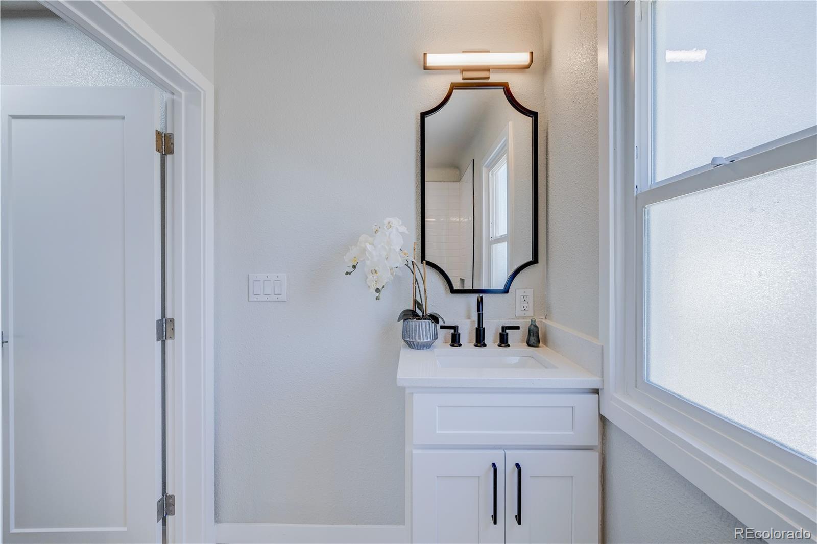 2932 Chase Street Wheat Ridge, CO 80214 - Photo 13 of 30 a bathroom with mirror a sink and vanity