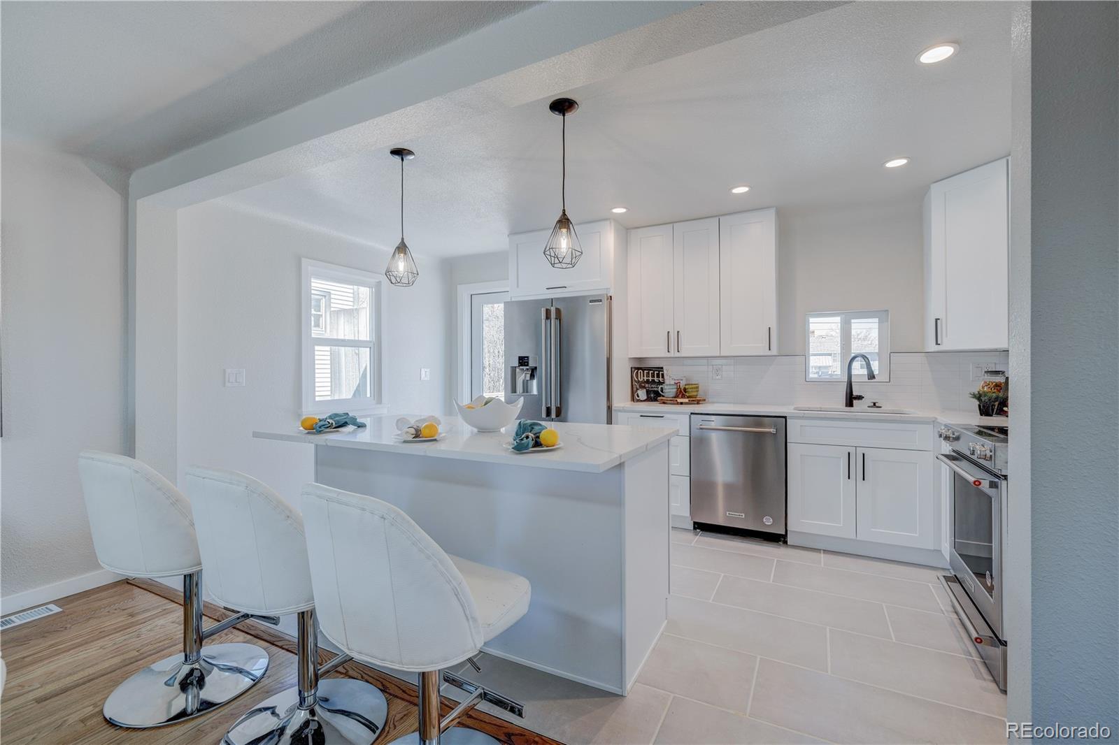 2932 Chase Street Wheat Ridge, CO 80214 - Photo 7 of 30 a kitchen with white cabinets and stainless steel appliances