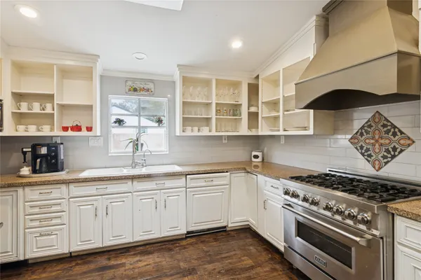 a kitchen with stainless steel appliances granite countertop a sink a stove and cabinets