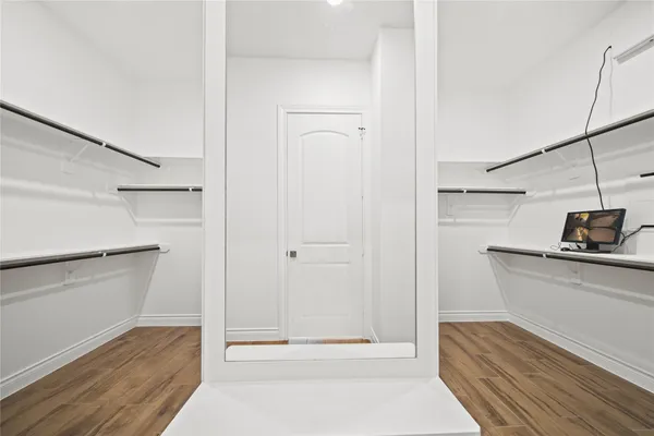 a walk in closet with wooden floor