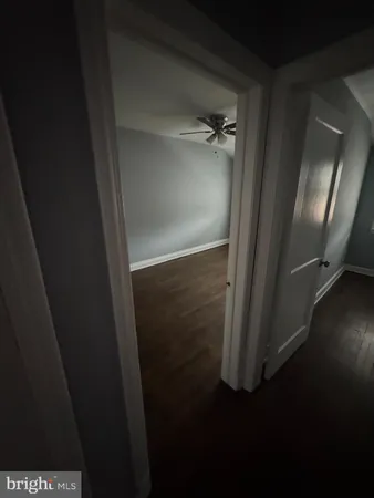 an empty room with wooden floor fan and window