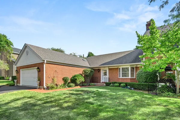 a view of a house with a big yard potted plants and large tree