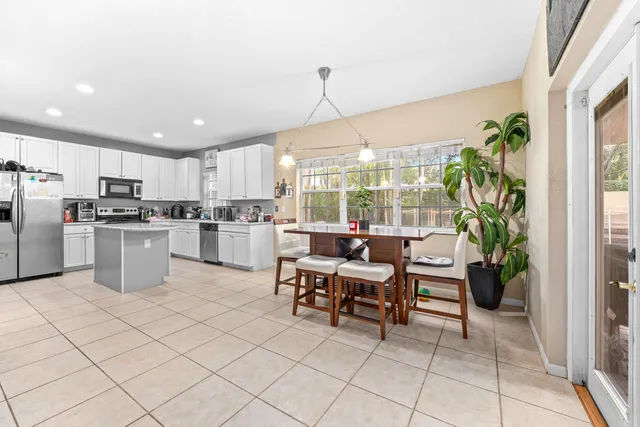 a kitchen with stainless steel appliances kitchen island granite countertop a refrigerator a stove a sink a dining table and chairs