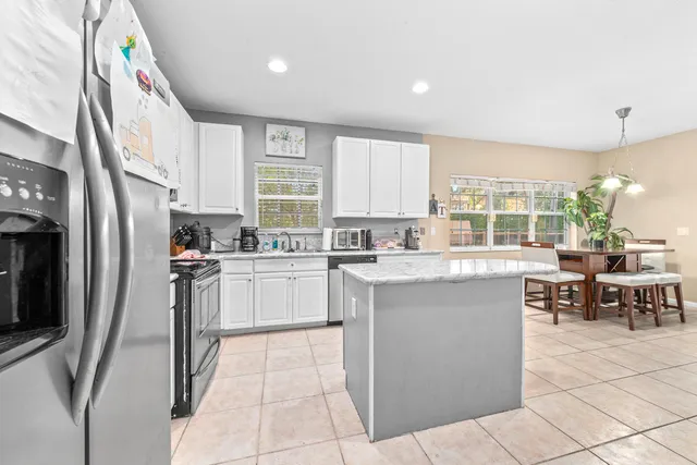 a kitchen with stainless steel appliances kitchen island granite countertop a refrigerator and a sink