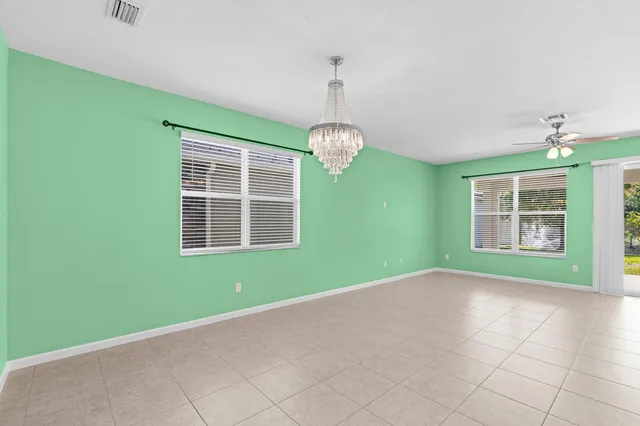 a view of an empty room with windows and chandelier fan