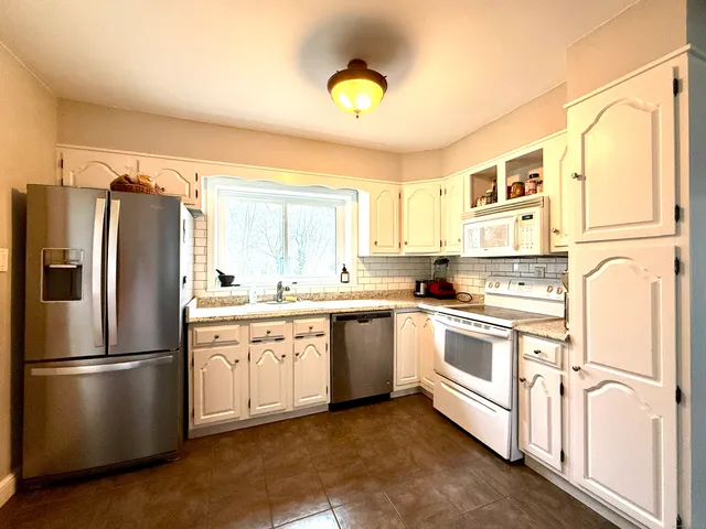 a kitchen with stainless steel appliances granite countertop a refrigerator a stove and a sink with wooden floors