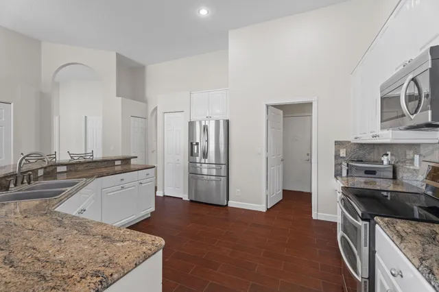 a kitchen with stainless steel appliances granite countertop a table chairs microwave and sink
