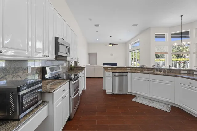 a large kitchen with stainless steel appliances granite countertop a sink stove and refrigerator