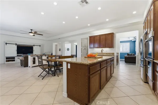 a kitchen with stainless steel appliances kitchen island granite countertop a refrigerator and a stove top oven
