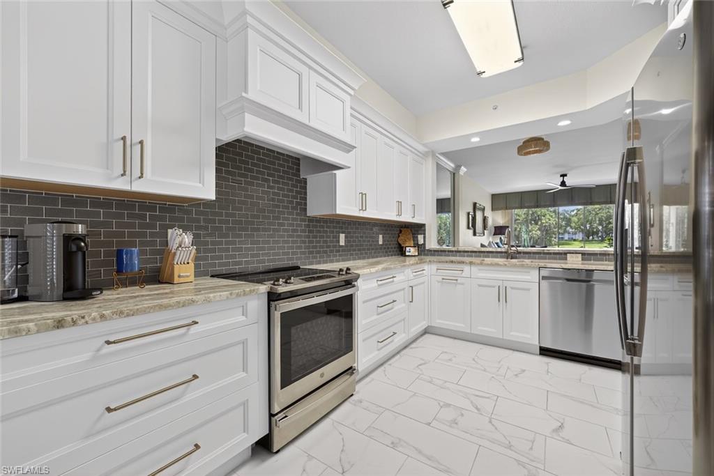 1940 Willow Bend Circle, Unit 102 Naples, FL 34109 - Photo 3 of 39 a kitchen with granite countertop cabinets and white stainless steel appliances