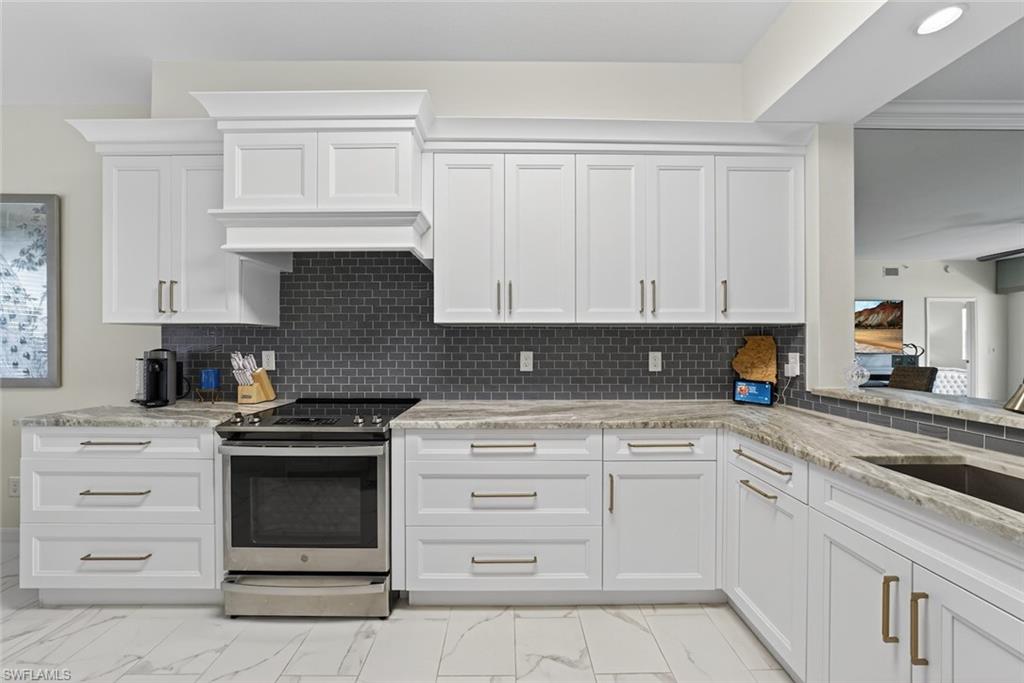 1940 Willow Bend Circle, Unit 102 Naples, FL 34109 - Photo 4 of 39 a kitchen with granite countertop white cabinets and stainless steel appliances