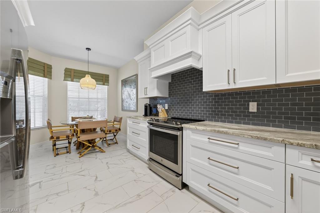 1940 Willow Bend Circle, Unit 102 Naples, FL 34109 - Photo 5 of 39 a kitchen with granite countertop cabinets stainless steel appliances and a dining table