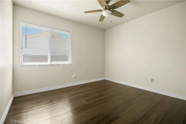 an empty room with wooden floor fan and windows