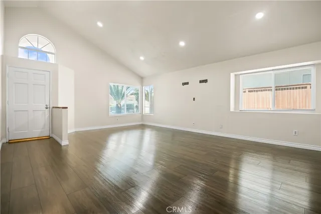 an empty room with wooden floor chandelier and windows