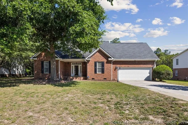 a front view of house with yard and trees in the background