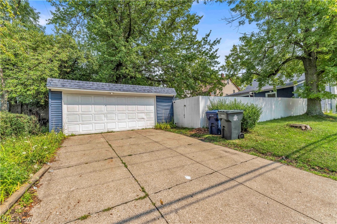 3731 Lowell Road Cleveland Heights, OH 44121 - Photo 27 of 29 Concrete driveway leading to a detached garage with a paneled door, blue siding, and a shingled roof