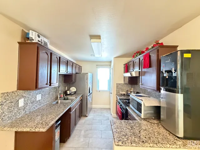 a kitchen with stainless steel appliances granite countertop a sink stove and refrigerator